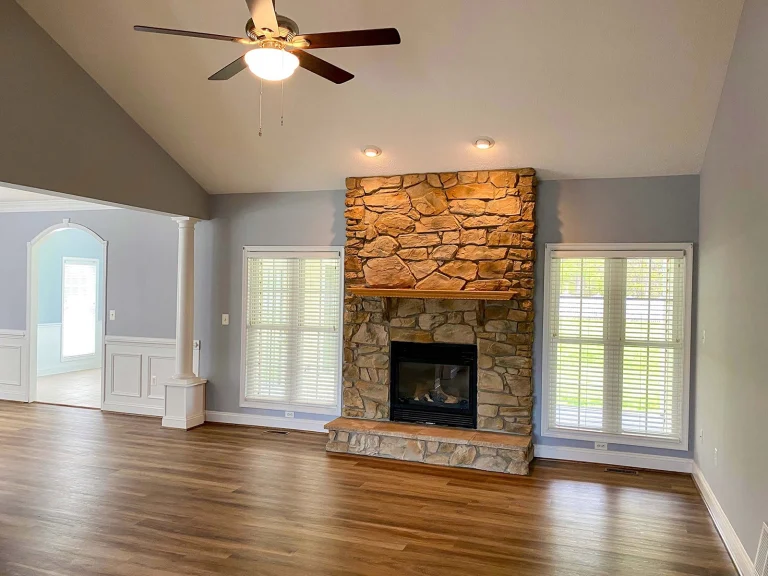 Living room with stone fireplace and wood flooring.