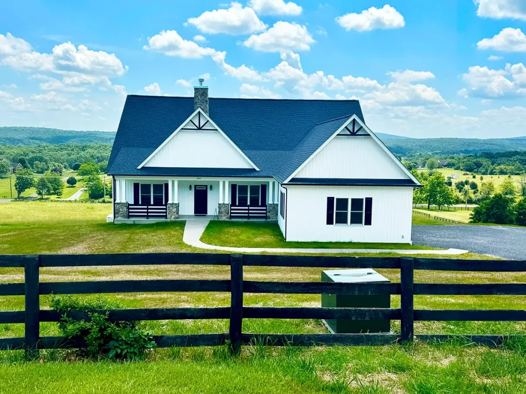 Wide view of a house with dark blue/grey roof with black railing surrounding the property
